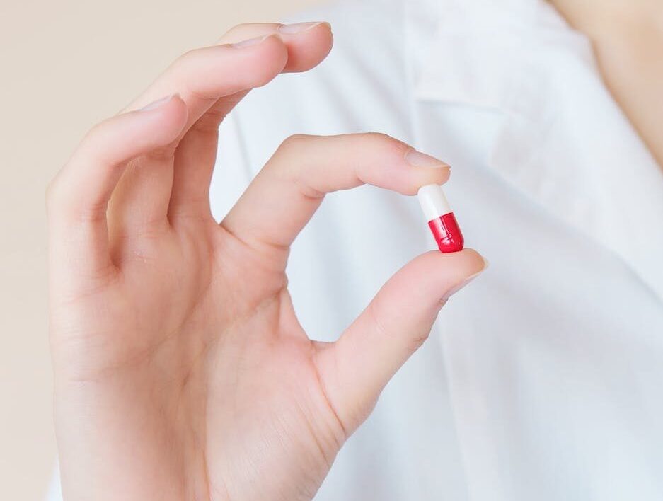A imagem mostra uma mulher segurando um antibiótico.