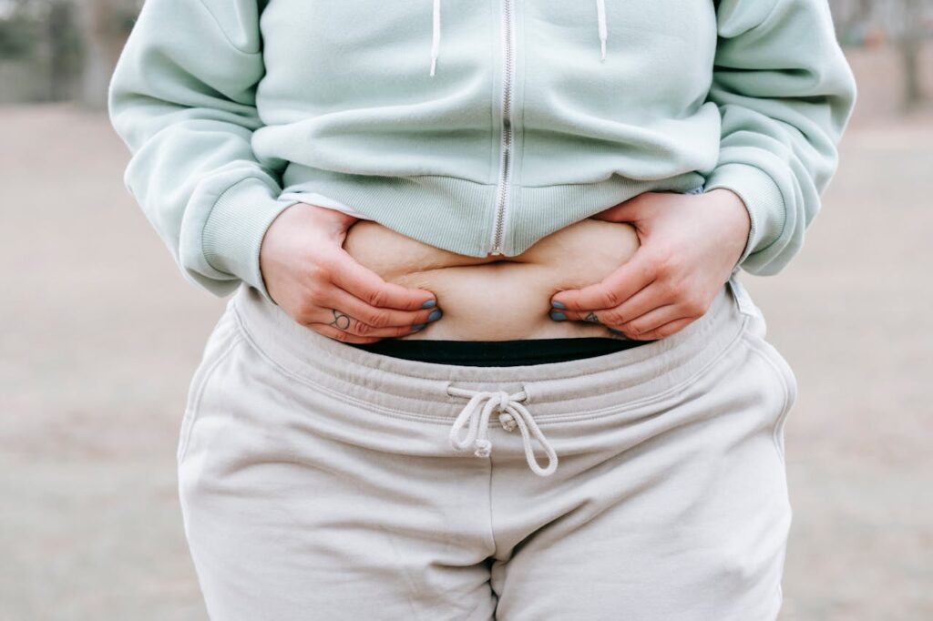 uma mulher com excesso de peso segurando a barriga.